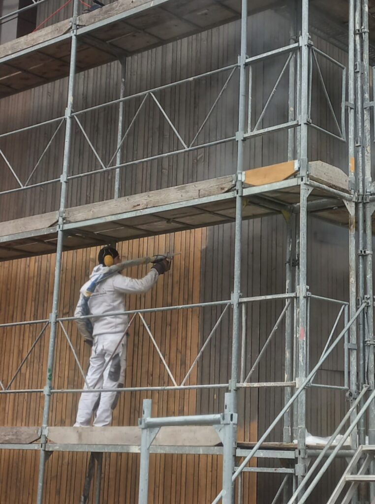 Ein Mitarbeiter der HD Oberflächen GmbH beim Trockeneisstrahlen einer Hauswand