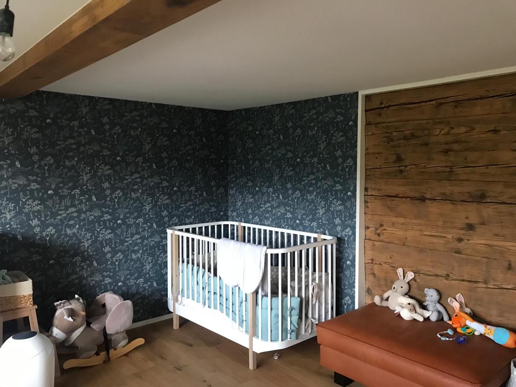 Ein Babyzimmer mit farbiger Tapete und weißer Decke als Beispiel für innere Malerarbeiten des Unternehmens HD Oberflächen GmbH